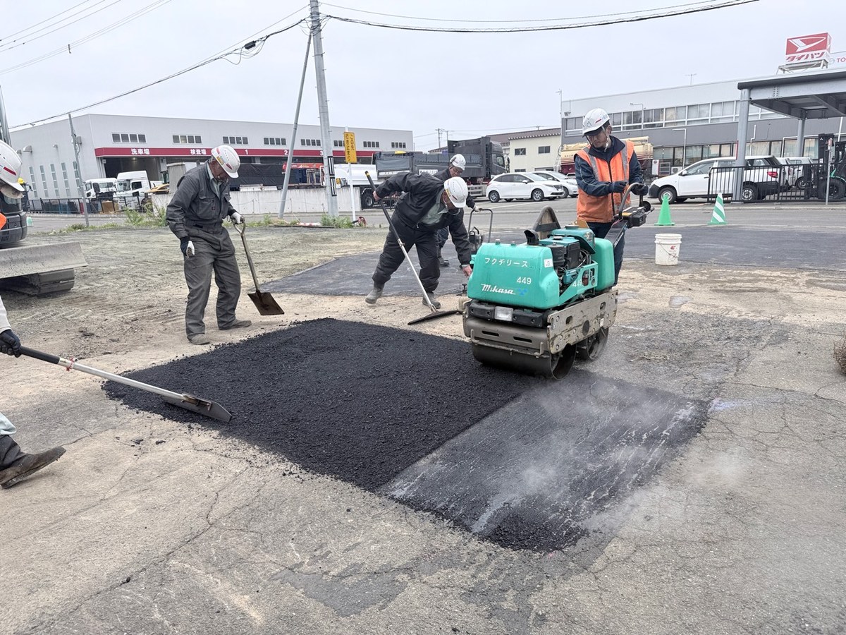 上総工業の作業員が転圧機を使ってアスファルト舗装を仕上げている様子